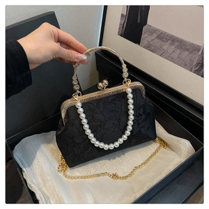 Close-up of black jacquard handbag with pearl handle and vintage gold metal clasp
