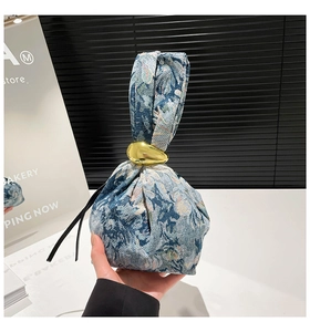 Detail of blue floral jacquard fabric tote with elegant gold metal ring ornament