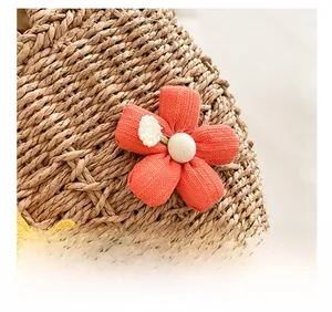 Macro shot of brown woven straw bag featuring 3D orange and yellow fabric flower accents