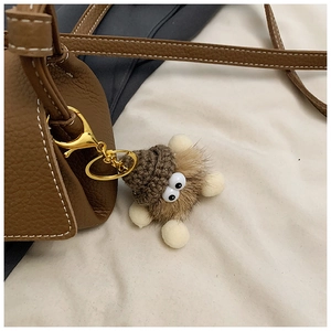 Détail d'une peluche monstre avec bonnet sur un sac bandoulière en cuir marron