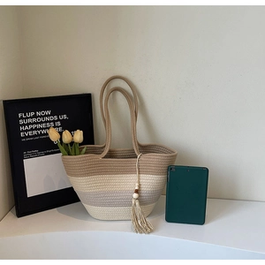 Detail of woven straw tote bag with color-block stripes and wooden bead tassels