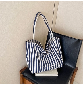 Close-up of a striped canvas tote bag featuring a front pocket on a black chair