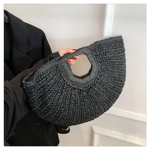Detailed texture of a black crescent woven handbag with integrated hollow handle design