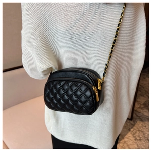 Detail of classic black quilted shoulder bag with dual gold zippers and chain strap