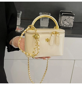 Détail du sac en cuir verni crème avec logo floral doré et bandoulière en chaîne