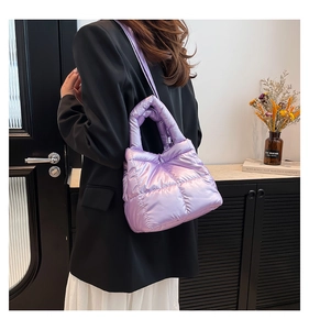 Detail of light purple quilted down handbag worn as a shoulder bag with black suit
