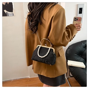 Detail showing pearl handle and gold chain strap of black crossbody bag on model