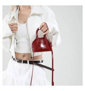 Détail du mini sac coquille rouge foncé en cuir verni brillant avec finitions argent