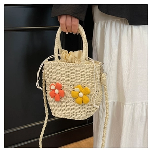 Close-up of woven straw bag with colorful floral appliques and secure drawstring liner