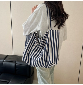 Rear view of a model wearing a large blue and white striped canvas bucket tote bag