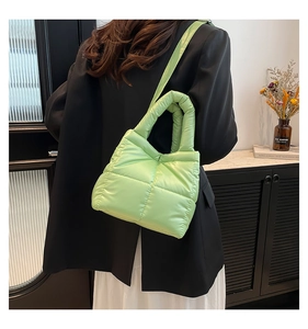 Detail view of avocado green quilted puffer bag featuring glossy texture and thick strap