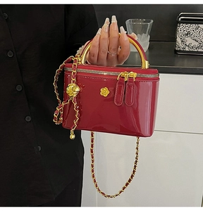 Detail of red patent leather square bag with gold chain strap and floral metal hardware