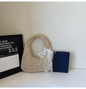 Detail of beige woven straw tote bag featuring a white lace bow accent and sturdy handles