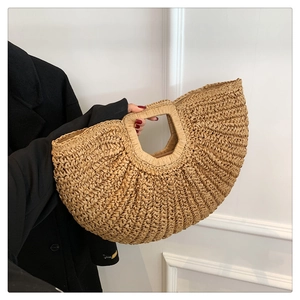Detail of hand-woven straw handbag showing natural texture and semi-circular design