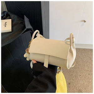 Gros plan d'un sac carré en cuir grainé blanc cassé avec pompon décoratif sur le côté