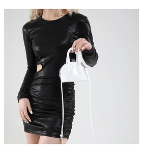 Gros plan d'un mini sac blanc brillant assorti à une robe à imprimé python découpée