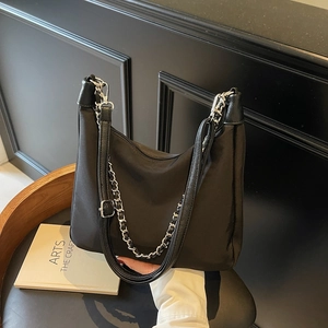 Black nylon tote bag with silver chain strap shown in a modern minimalist setting