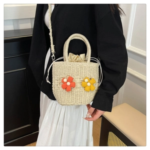 Detail of woven straw bag with decorative fabric flowers and pearl accents