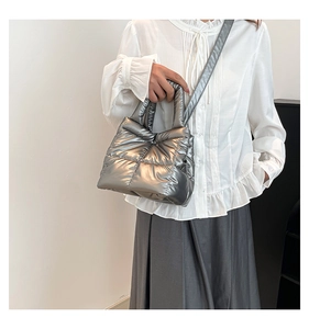 Close-up of metallic silver quilted down bucket bag with padded texture and crossbody strap