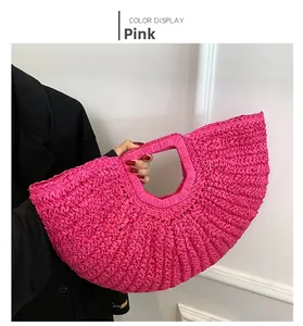 Close-up of pink semicircular woven handbag with integrated handle held by a model