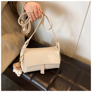 Détail d'un sac bandoulière beige en similicuir grainé avec pendentif en peluche
