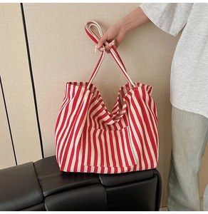Detail of red and white striped canvas tote bag with front pocket and durable handles