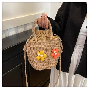 Detail of woven straw handbag with colorful floral 3D accents and drawstring lining
