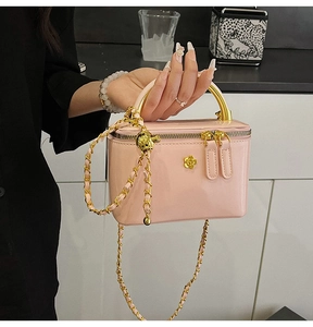 Détail du mini sac verni rose pâle avec bijouterie camélia dorée et bandoulière chaîne