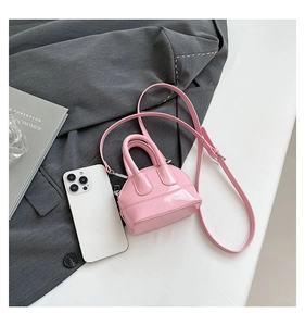 Mini sac bandoulière en cuir verni rose à côté d'un smartphone pour comparer la taille
