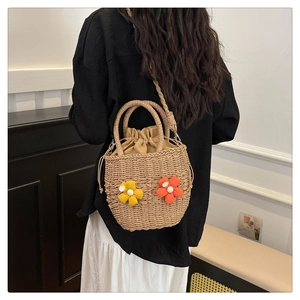 Detail of woven straw bucket bag with floral accents and adjustable shoulder strap