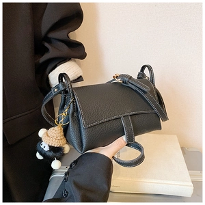 Sac bandoulière en cuir noir à surpiqûres blanches avec un pendentif en peluche