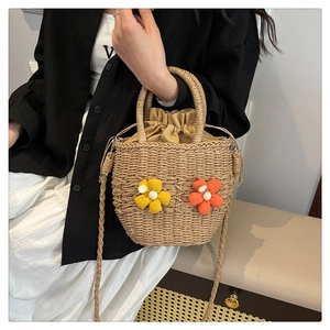 Detail of woven straw handbag with vibrant 3D floral accents and drawstring liner