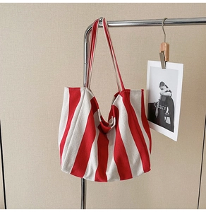 Detail of red and white striped canvas tote bag hanging on a minimalist silver metal rack