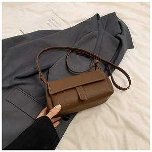 Détail du sac carré en cuir marron avec surpiqûres contrastées et fermeture à rabat chic