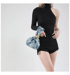 Detail of floral woven handbag featuring a large gold metal buckle and jacquard fabric texture