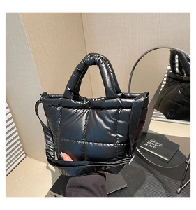 Close-up of black quilted puffer tote bag featuring glossy waterproof fabric and strap