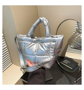 Detail of silver metallic quilted tote bag featuring reinforced stitching and crossbody strap