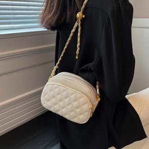 White quilted crossbody camera bag with gold chain and ball adjuster shown on a model