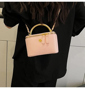 Vue détaillée du mini sac en cuir verni rose avec poignée dorée et emblème floral