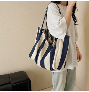 Lifestyle shot of striped canvas tote bag on model showing large capacity and texture