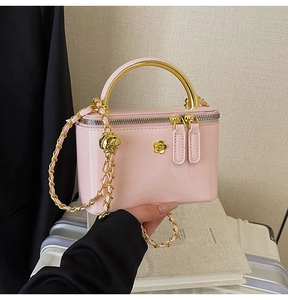 Gros plan du mini sac boîte en cuir verni rose avec camélia doré et poignée métal