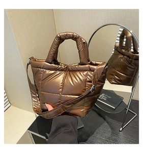 Close-up of metallic brown quilted puffer tote bag with thick handles and glossy finish