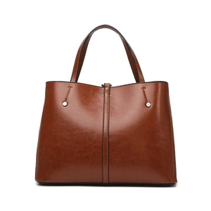 Classic caramel brown leather tote bag with vertical seam and silver rivets on white background