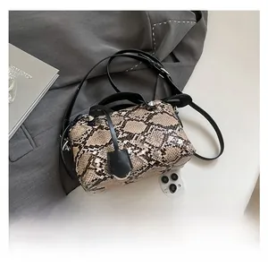 Top view of snake pattern crossbody bag with black handles on a grey suit jacket fabric