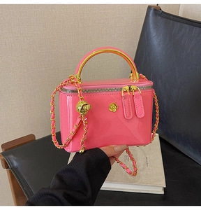 Détail du mini sac boîte en cuir verni rose avec camélia doré et bandoulière chaîne