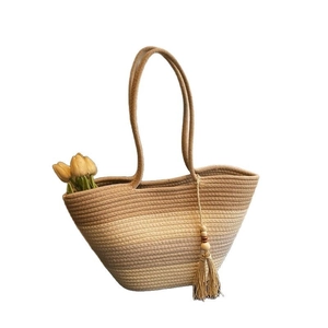 Handwoven gradient straw tote bag with long handles and tassel charm in a minimalist style