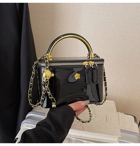 Détail du sac à bandoulière en cuir verni noir avec fermoir fleur dorée et chaîne