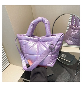 Detail of lavender puffer bag showing shiny quilted texture and metal strap buckles