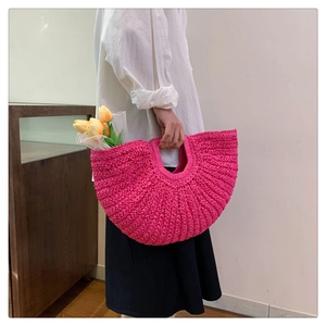 Detail of rose pink woven straw handbag with tulip flowers in a minimalist setting