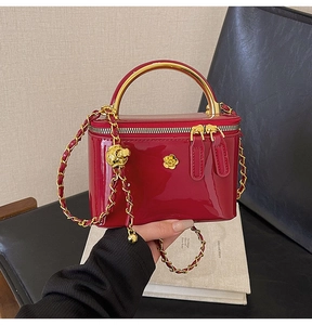 Détail du mini sac carré en cuir verni rouge avec poignée dorée et fermoir fleur